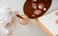 Målarpalett med rosa färger, pensel, duk och vit tygtrasa